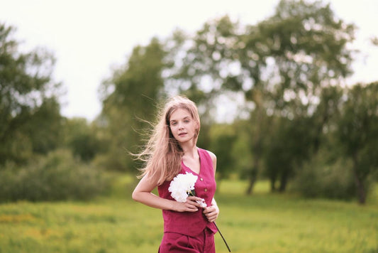 modelka w różowej kamizelce z lnu na tle łąki i zielonego lasu